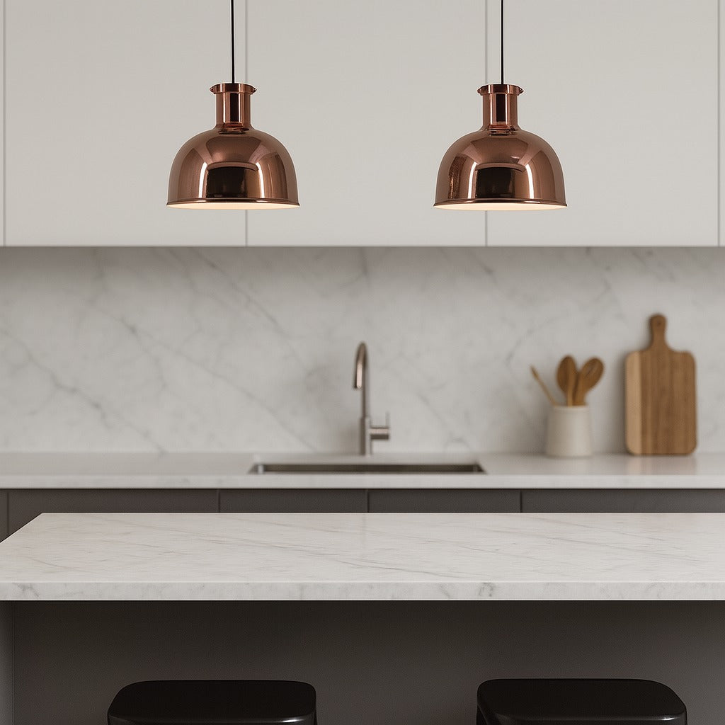 Modern kitchen with copper pendant lights, marble countertop, and white cabinets.